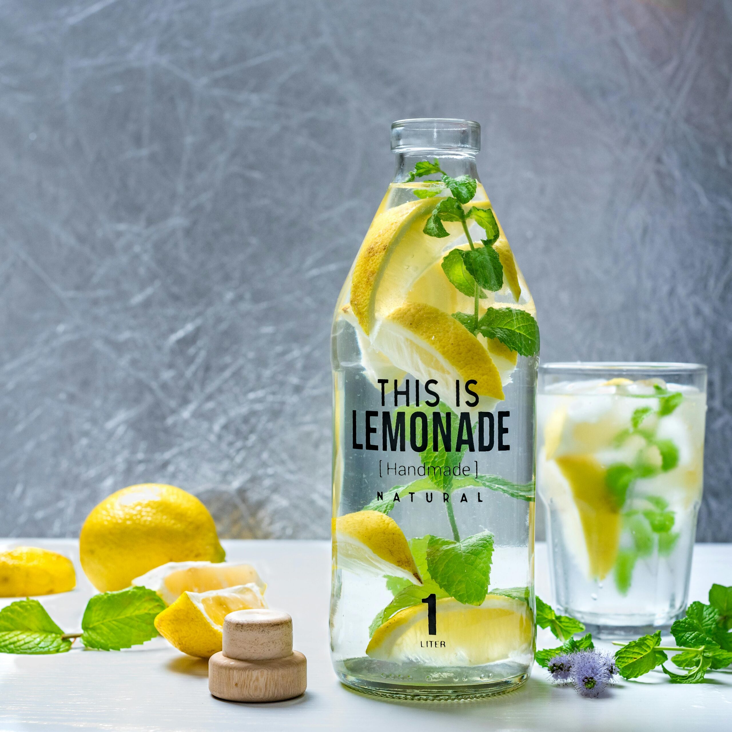Chilled lemonade with fresh lemons and mint leaves in a bottle, perfect for a refreshing summer drink.
